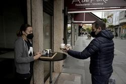 Un home recolle uns cafés dun establecemento coas novas restricións para a hostalaría / M. Dylan - Europa Press.