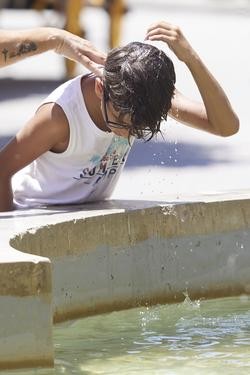 Un neno bota auga pola cabeza para refrescarse durante unha onda de calor / Joaquin Corchero