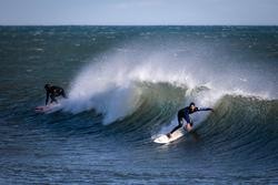 Dous surfeiros surfean unha onda na praia de Bogatell, a 17 de xaneiro de 2023, en Barcelona, Catalunya (España). Kike Recuncho - Europa Press - Arquivo