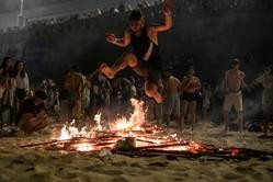 Unha persoa salta unha fogueira durante a Noite de San Xoán, na praia de Riazor / M. Dylan - Arquivo