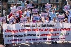 Varias persoas cunha pancarta e carteis durante unha concentración das vítimas de Angrois, na estación de tren de Santiago, a 24 de xullo de 2024, en Santiago de Compostela / César Arxina