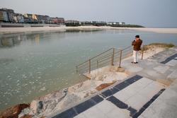 Unha persoa fotografa a pleamar no espigón de Foz, xunto á praia da Rapadoira /  Carlos Castro