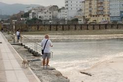 Arquivo - Varias persoas pasean durante a pleamar no espigón de Foz, xunto á praia da Rapadoira / Carlos Castro